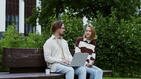 dos adultos jóvenes colaborando en una computadora portátil en un parque