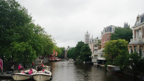 boats with tourists in canal in amsterdam, netherlands - wide shot
