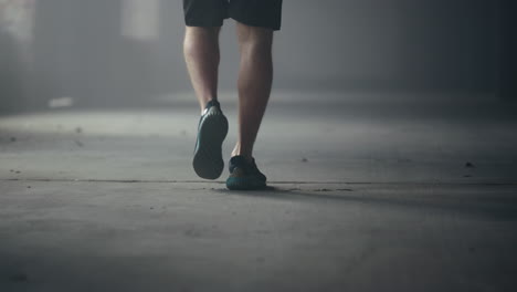 male athlete feet walking in loft building. man legs going for training