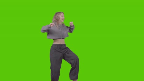 full length studio shot of young woman having fun dancing against green screen 4