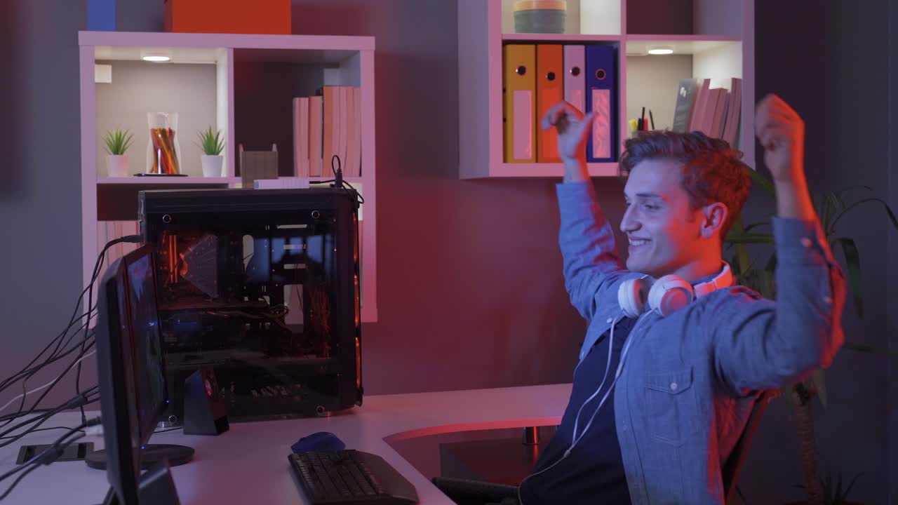 Junger Mann spielt Videospiel am Computer, jubelt und gewinnt