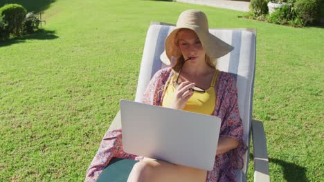 Mujer-Caucásica-Usando-Una-Computadora-Portátil-Mientras-Toma-El-Sol-En-Una-Tumbona-En-El-Jardín