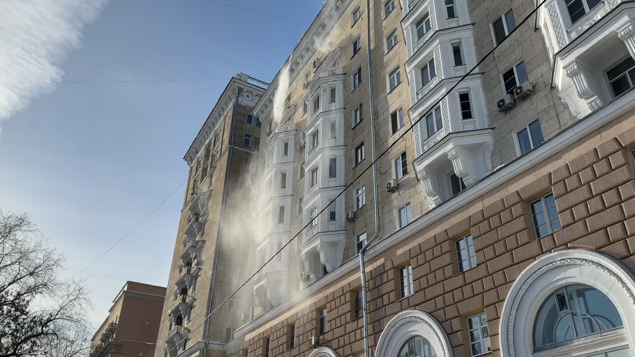 Se arroja nieve del tejado de un edificio de varias plantas.