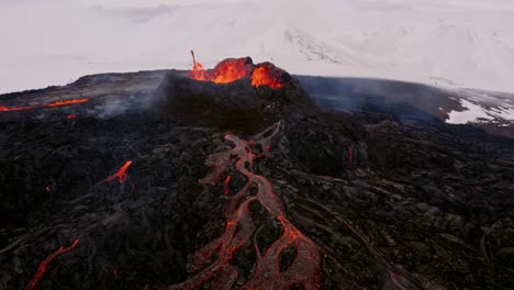 un dron de 4k captura imágenes aéreas, presentando tomas cinematográficas y distintivas de una boca de volcán abierta durante la erupción, con lava en cascada a través de campos naturales