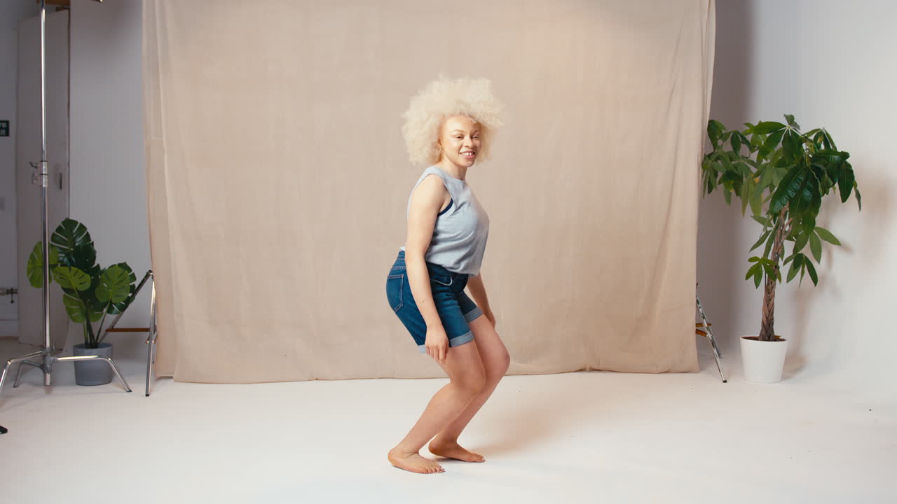 Studio Portrait Shot Of Casually Dressed Body Positive Albino Woman Jumping In The Air