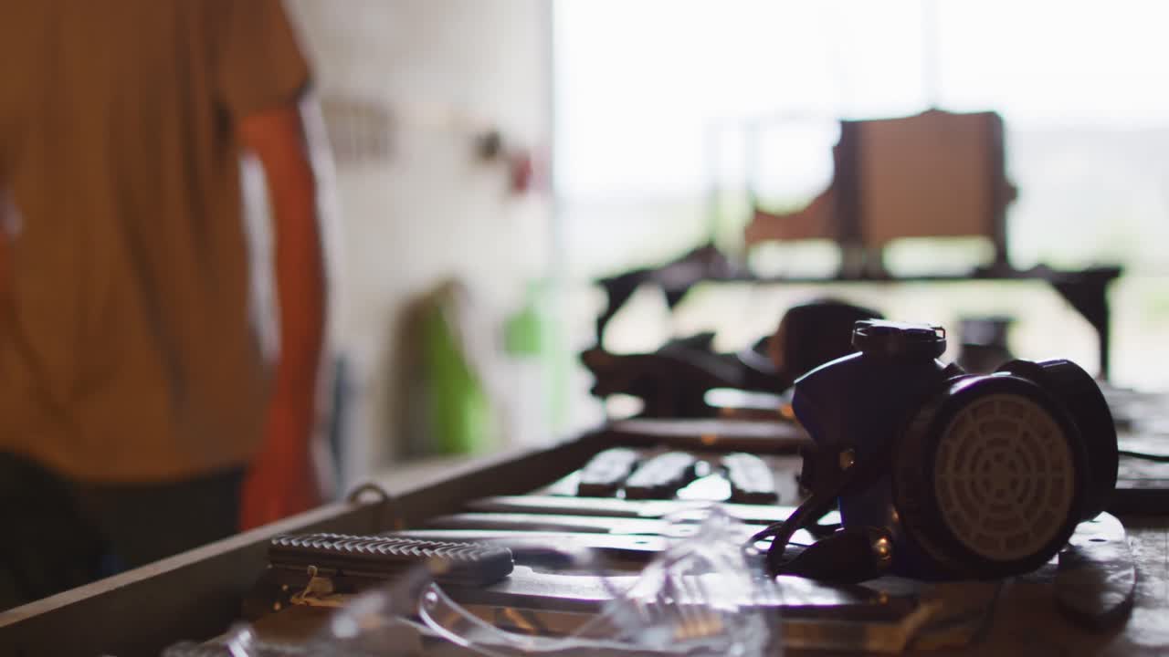 Plan taille d'un forgeron caucasien marchant dans un atelier avec des outils sur une table.
