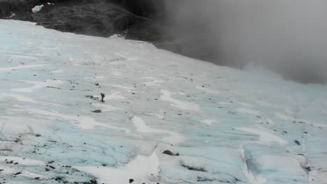 Solo-explorer-traverses-the-Brewster-Glacier,-navigating-its-frozen-terrain-amidst-the-towering-peaks-of-the-Southern-Alps-in-New-Zealand