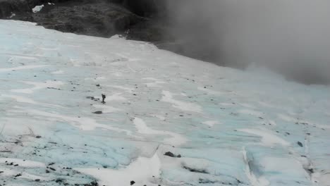 un explorador en solitario atraviesa el glaciar brewster, navegando por su terreno congelado en medio de los altos picos de los alpes del sur en nueva zelanda.