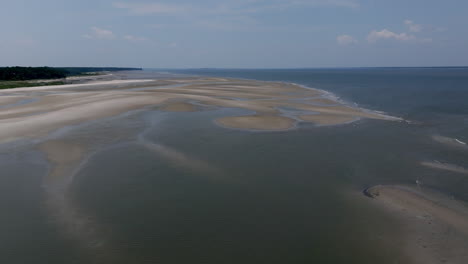 gentle waves lap against patterned sandbanks, creating elegant lines and shapes as the beach flows into deeper water offshore