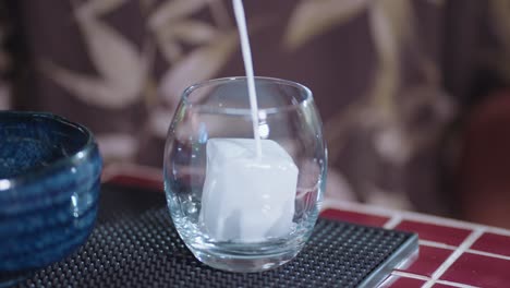 pouring milk into a glass with ice
