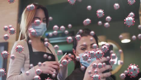 animation of coronavirus cells over caucasian female hairdresser and woman wearing face masks