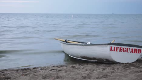 lifeguard's boat docked on the sand by the sea shore - medium shot