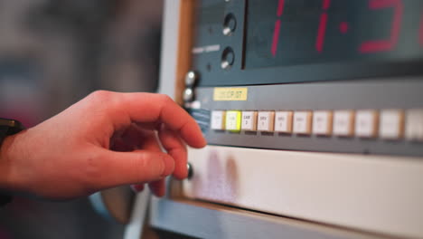 close-up of hand pressing "cam 3" button on broadcast control panel with digital timer display visible, used in television production environments to switch camera feeds