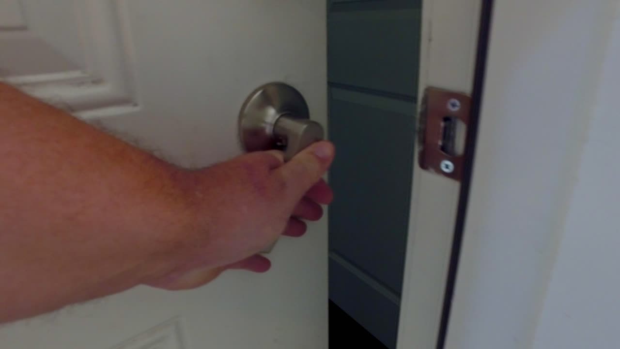 primo piano della mano che gira la manopola della porta per aprire la porta nell'appartamento per rivelare l'altro lato