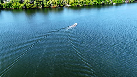 motor boat moves slowly by the waterscape of the rugged river. lush greenery at the waterfront at backdrop. sri lanka nature. aerial view.