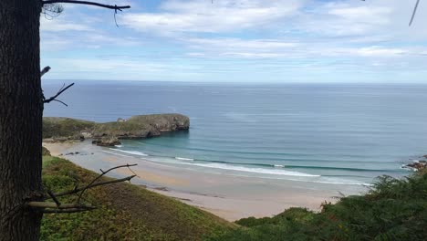 Peaceful view of Torimbia beach in Asturias with soft waves and green cliffs