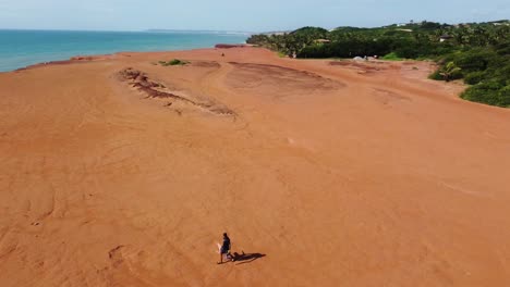 solo walker along vast desert beachside cliffs with vibrant red dirt