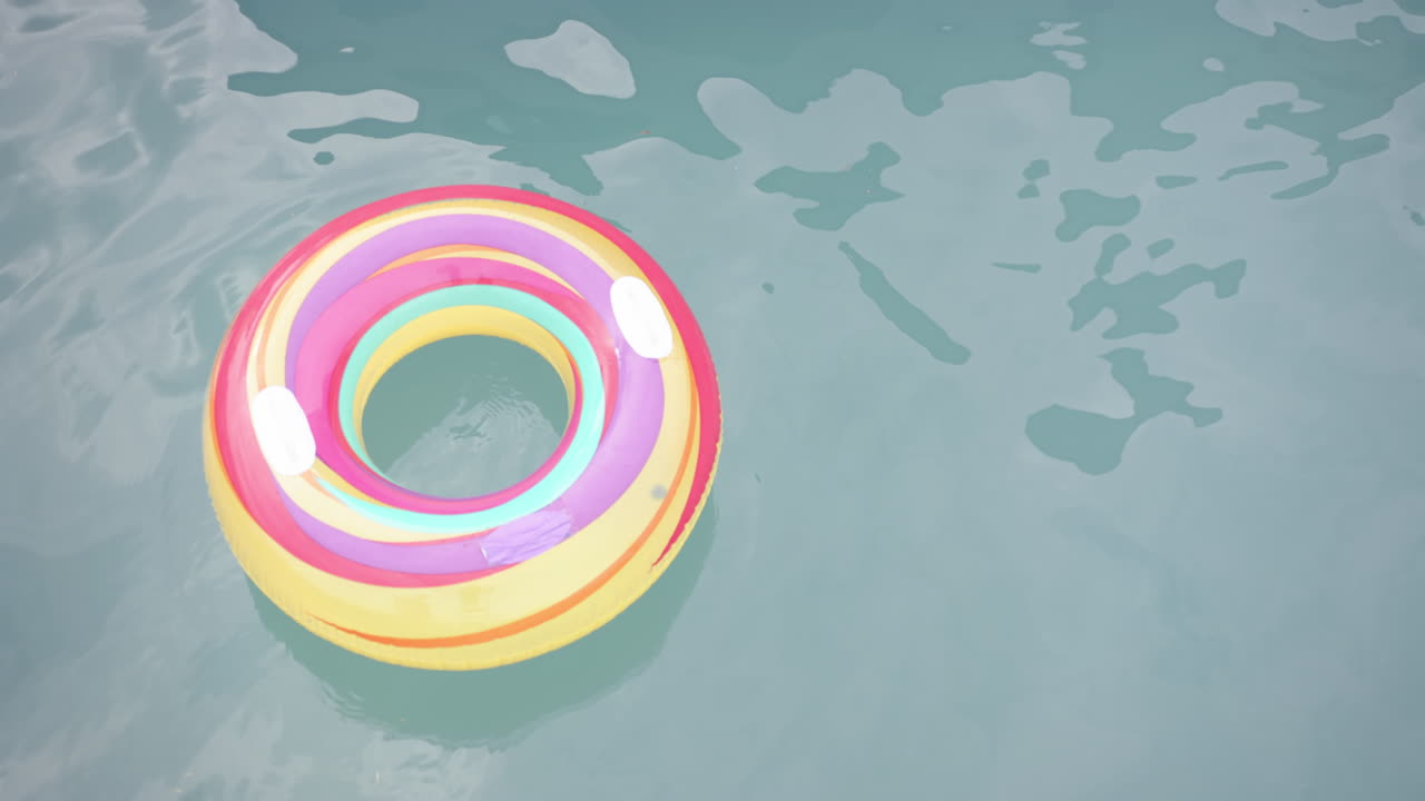 A colorful inflatable ring floats on a pool''s surface