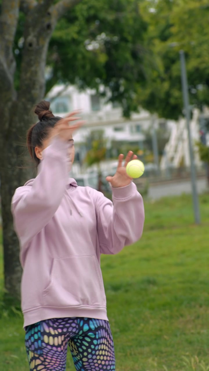 Young Woman Juggling Tennis Balls in a Park