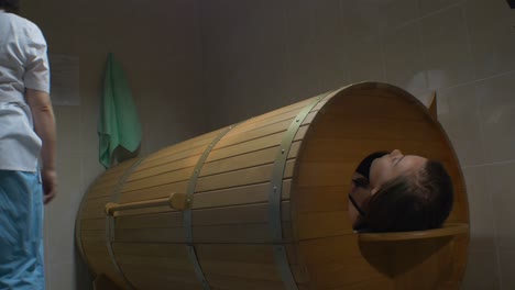 woman relaxing in a wooden barrel sauna