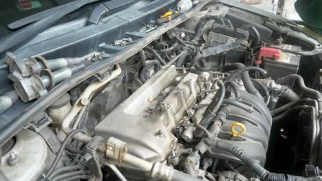 Display-of-the-engine-of-vehicle-under-the-hood-while-screws-and-bolts-placed-and-separated-carefully-on-the-windshield-gutter-while-the-mechanic-fixes-the-problem,-auto-repair-shop,-Bangkok,-Thailand