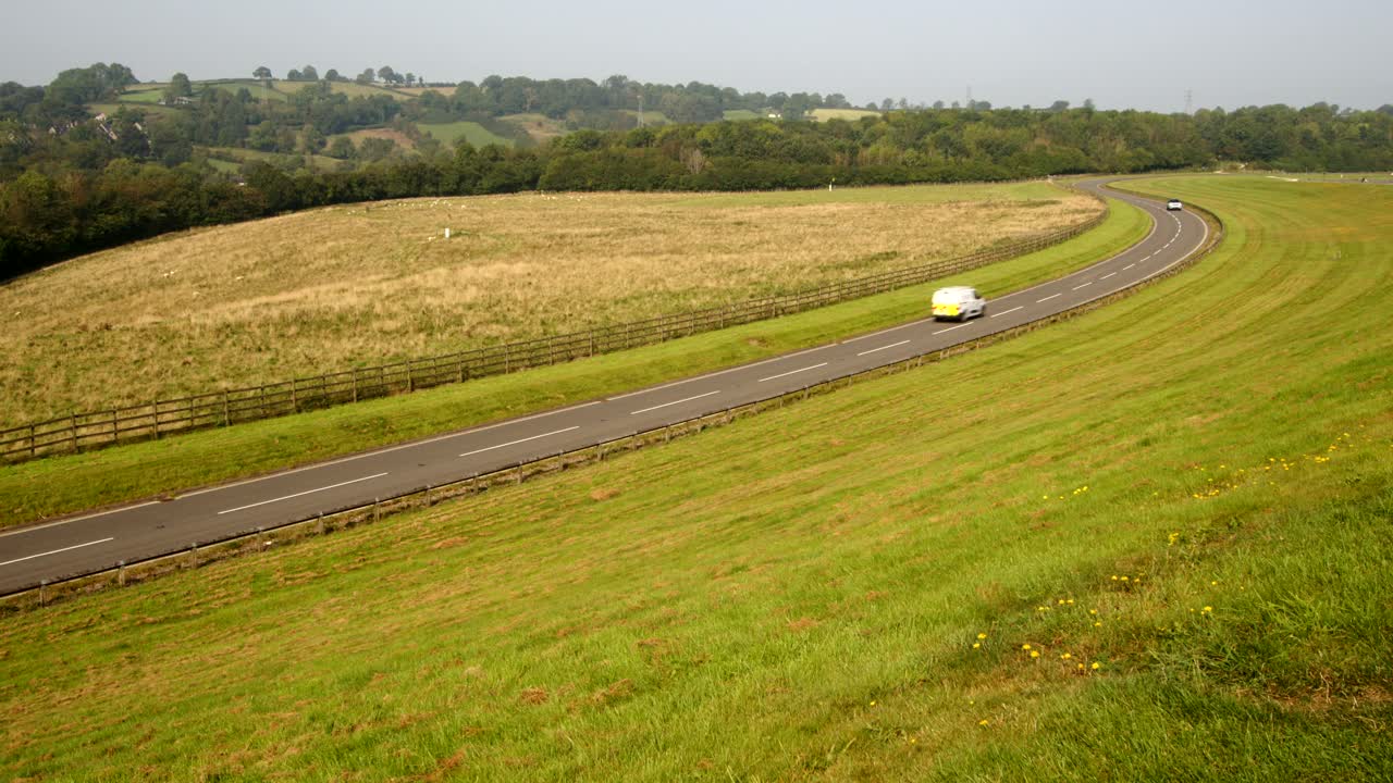 Wide shot Looking up Carsington water dam, with the dam road to the left frame with traffic