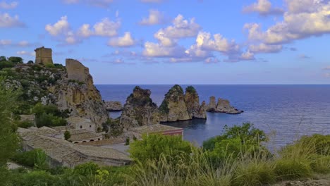 clouds over stacks or faraglioni of scopello and torre doria tower in sicily