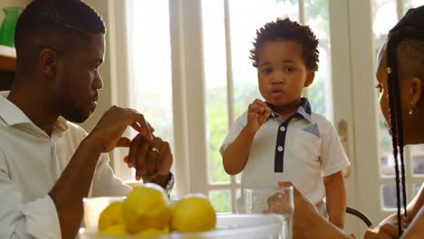 Vista-Frontal-De-Una-Joven-Familia-Negra-Comiendo-En-La-Mesa-Del-Comedor-En-La-Cocina-De-Una-Cómoda-Casa-4k