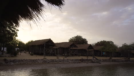 eco-friendly-wooden-and-clay-houses-in-Senegal-africa-remote-rural-village-next-to-natural-lake,-African-scenic-landscape