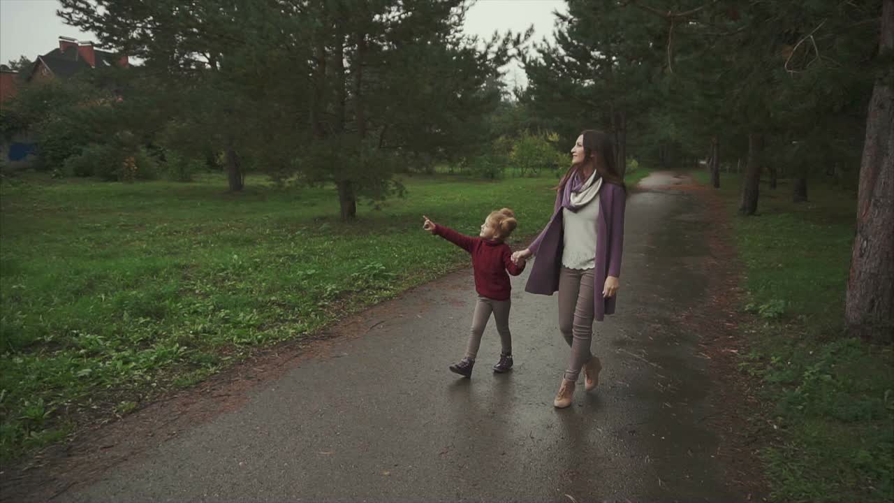 мать и дочь гуляют в парке в дождливый день