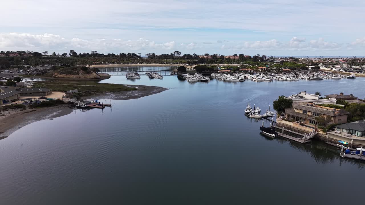 Cảnh quay từ trên cao mượt mà ghi lại thuyền, bến tàu và mặt nước vịnh yên tĩnh trong điều kiện ánh sáng ban ngày rõ nét