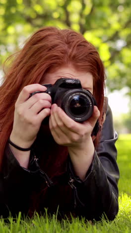 pretty redhead taking a photo in the park