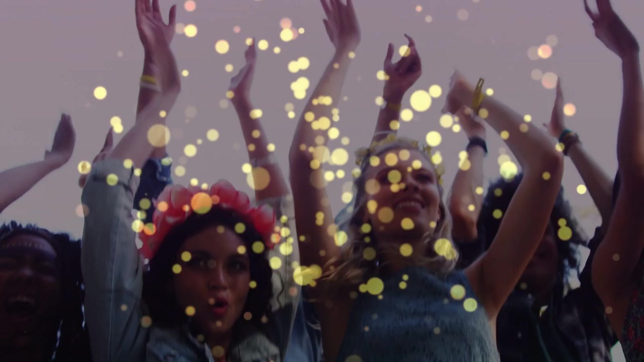 Folla di un evento a ritmo, che alza le braccia e festeggia, con bokeh dorato che si sposta e cresce attraverso l'inquadratura.