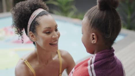 madre y hija afroamericanas cubriendo con toalla junto a la piscina, cámara lenta, sin alteración.