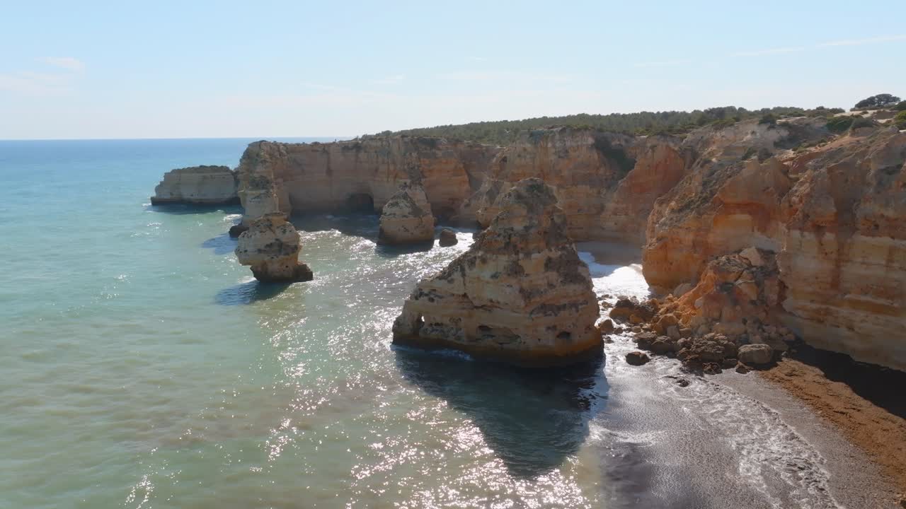 Costa de Praia da Marinha, Algarve, Portugal, con fuerte oleaje, vista aérea en órbita con efecto parallax.