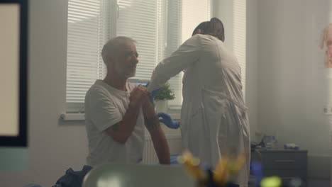 physician vaccinate elderly patient in hospital. senior man getting vaccine.