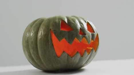 Close-up-view-of-scary-face-carved-halloween-pumpkin-against-grey-background