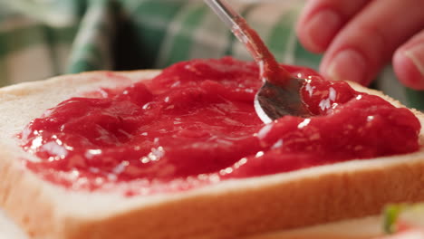 spreading strawberry jam on toast