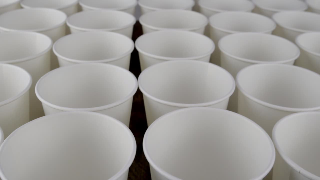 fila de taza de papel blanco desechable para café o bebida caliente en un fondo oscuro girar lentamente.