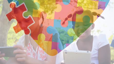 Animation-of-colourful-puzzle-pieces-heart-over-schoolgirls-using-tablets