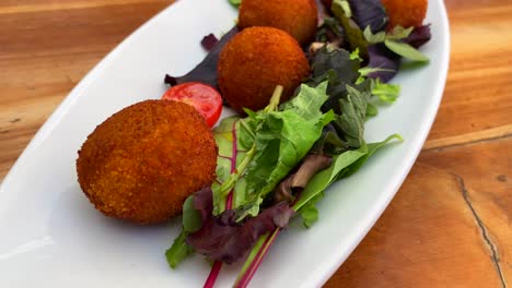 traditional spanish croquettes with iberian ham, tasty and crispy breaded starter dish with salad in a restaurant, tapas in ibiza spain, 4k shot