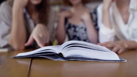 Unrecognizable-students-reading-book-together-in-the-library,-Close-Up