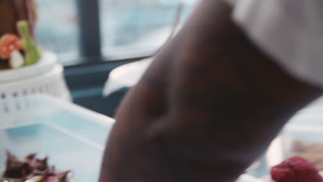 woman frosting muffin and placing on tray at a bakery, mid section