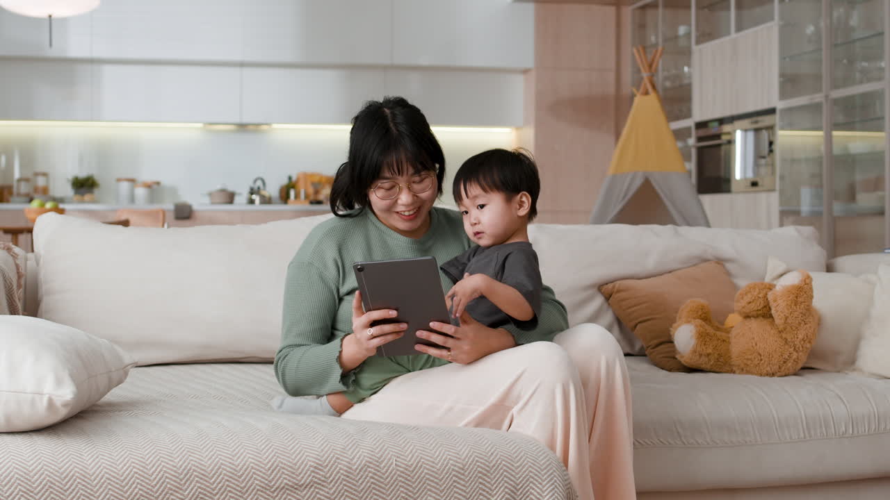 Mother and Child Watching Tablet on Sofa