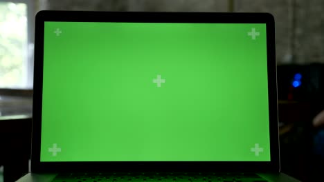 close moving shot of laptop's display with chromakey in modern office