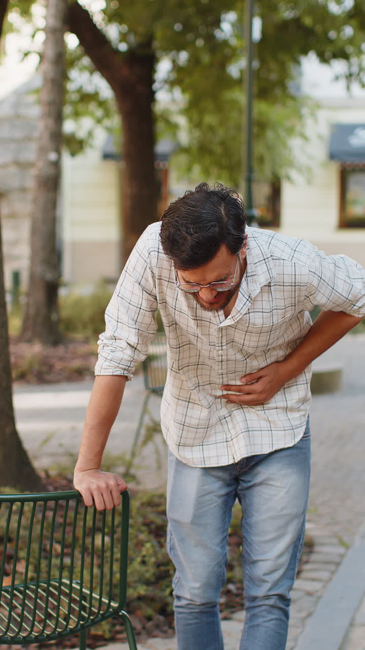 Indian young man traveler feeling sudden strong abdominal stomach ache gastritis problem on street