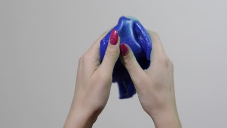 woman hands playing with oddly satisfying blue slime gooey substance. antistress