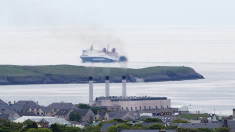 Telephoto-shot-of-a-passenger-ferry-sailing-passed-the-smoke-from-an-active-power-station