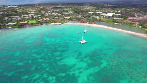 sailboats anchored in the turquoise bay near anaehoomalu on the big island of hawaii and nearby hotels - ascending aerial view