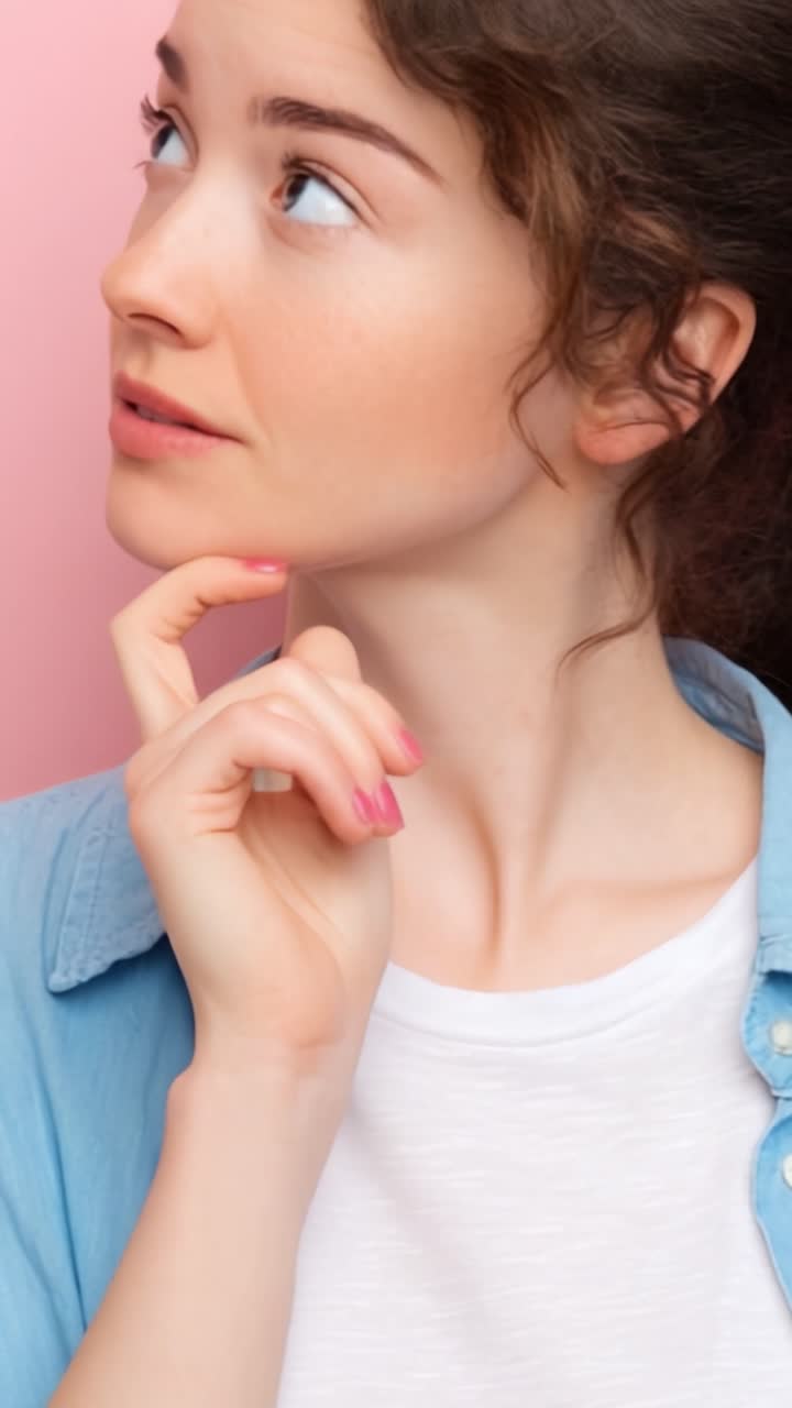 Una giovane donna che contempla i suoi pensieri con curiosità e introspezione su uno sfondo rosa tenue, catturando un momento di riflessione e processo decisionale